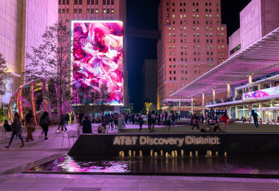 The AT&T Discovery District illuminated by large-scale digital activations, including towering LED wall and interactive globe. These dynamic visuals transform the urban space into a vibrant, immersive environment that blends technology with public art.