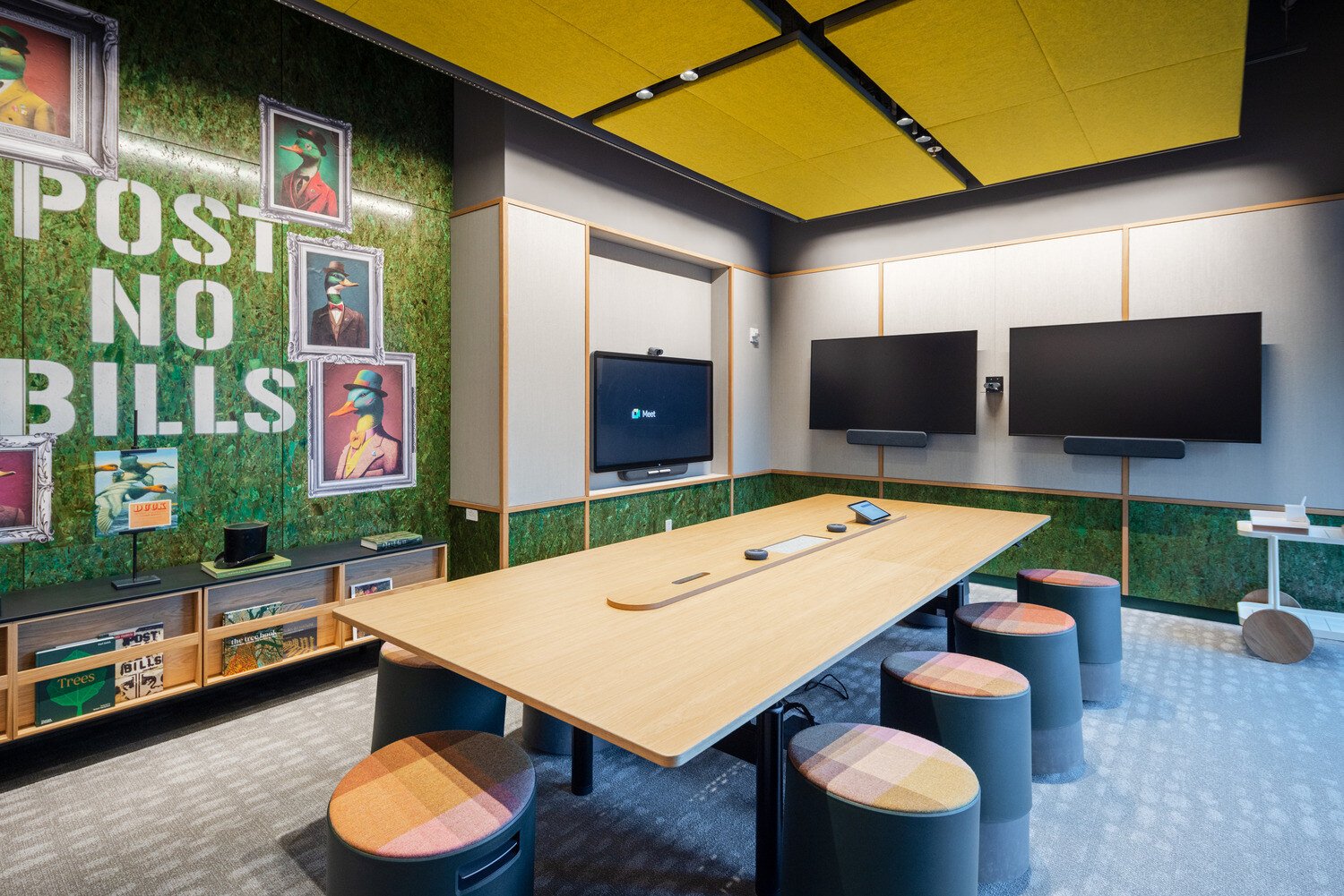 A boardroom with three tv displays and a desk in the middle