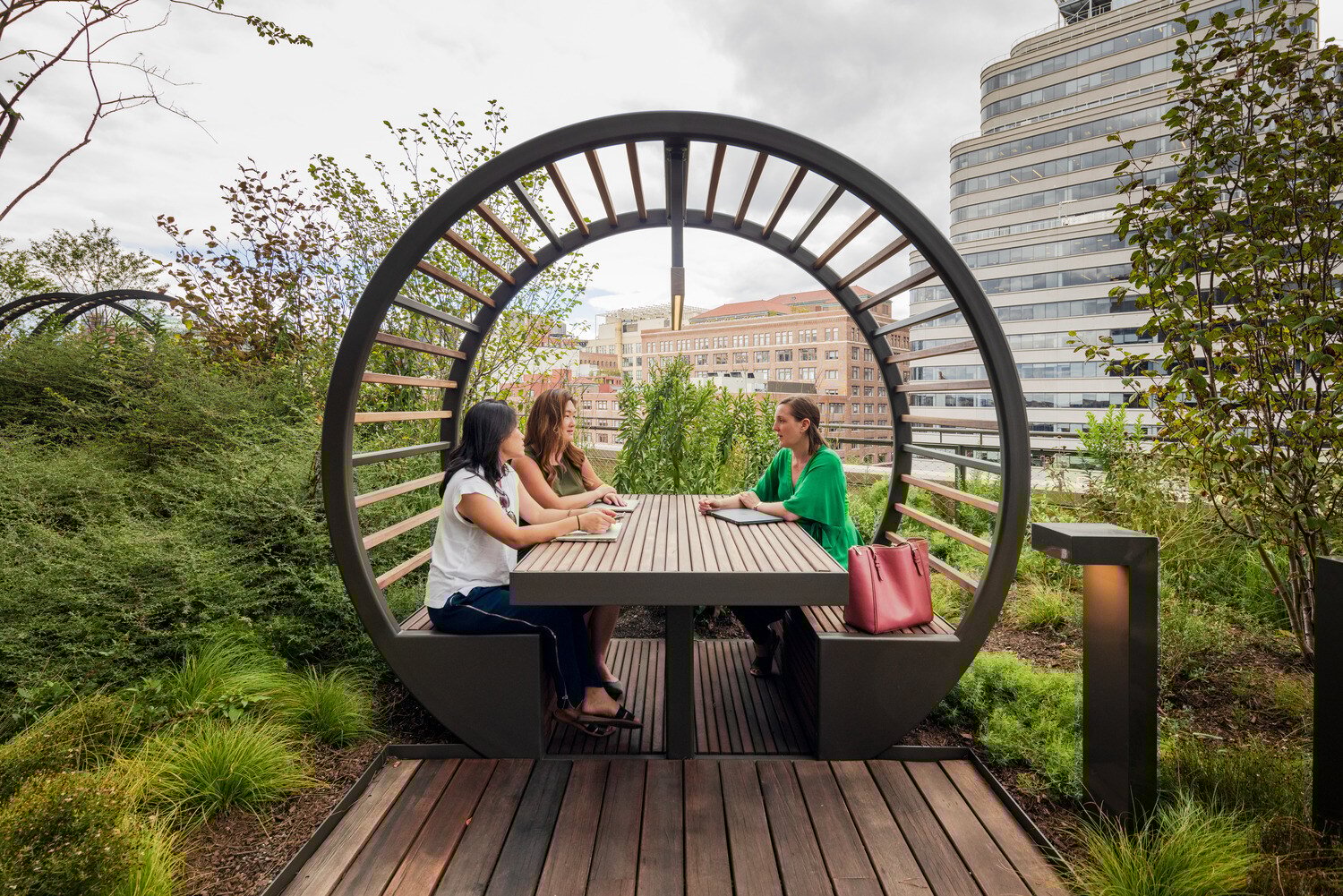 3 people talking at a table under the circular pergola