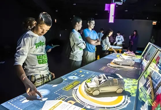 A boy interacting with a projection mapped model of a car at the Museum of Industry.