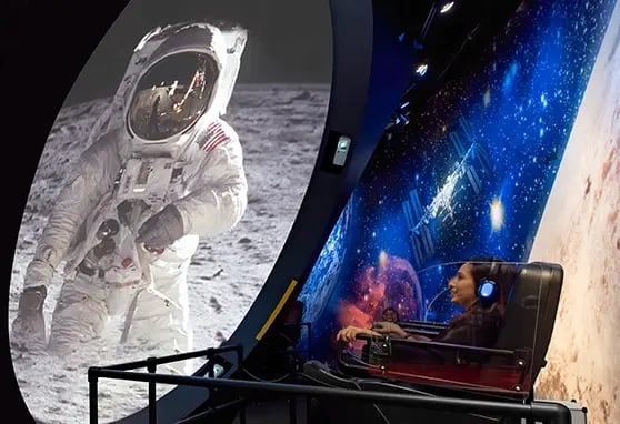 A guest to the New Jersey Hall of Fame enjoying an attraction where shes looking into a projection mapped dome showing an astronaut.