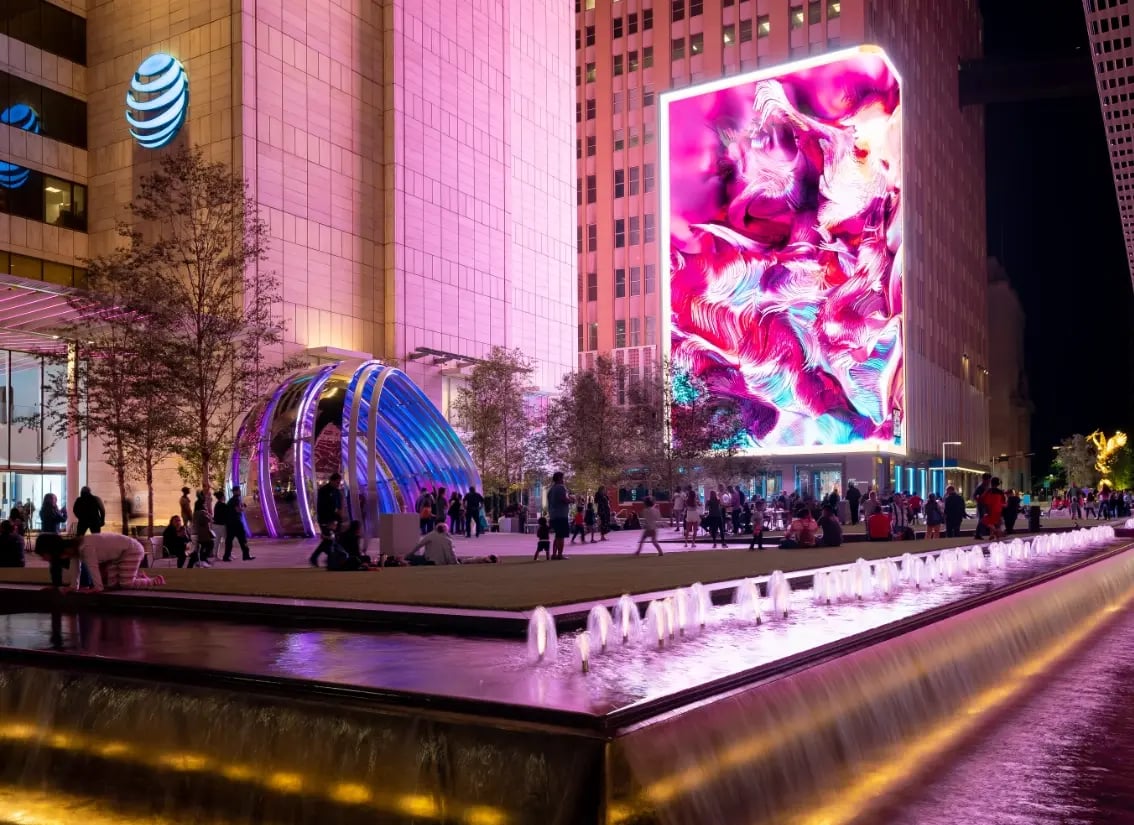 A large outdoor video wall showing bright vivid pink colors in a courtyard.