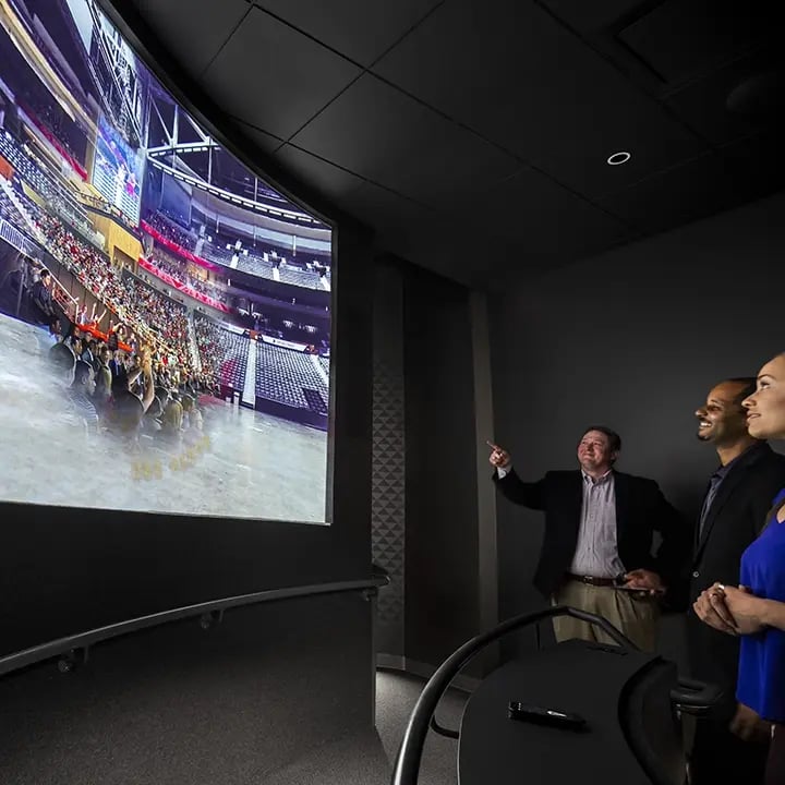 A man gestures toward a large LED video wall, possibly explaining its content, installation or functionality as part of a guided walkthrough or system review.