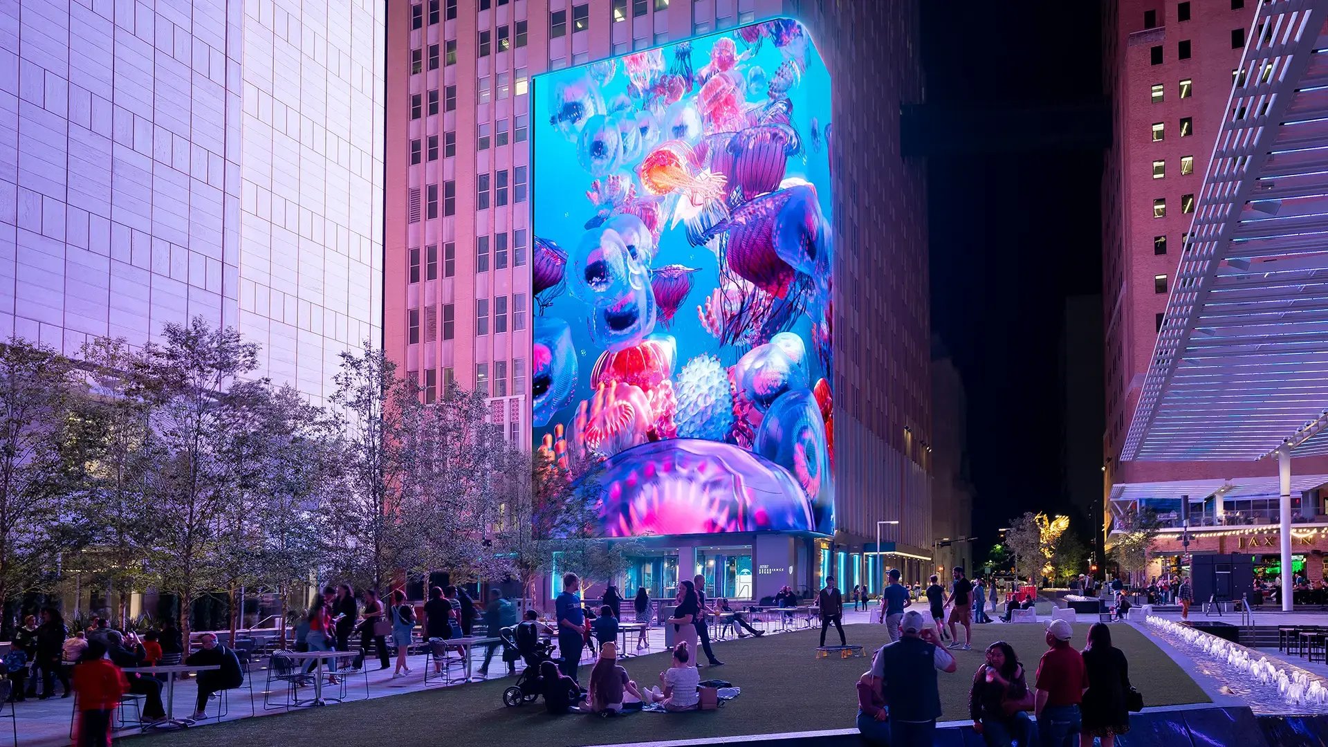 A massive 12,000-square-foot outdoor LED wall at the AT&T Discovery District displays vibrant visuals and brand messaging in a public plaza, drawing in visitors with dynamic content.
