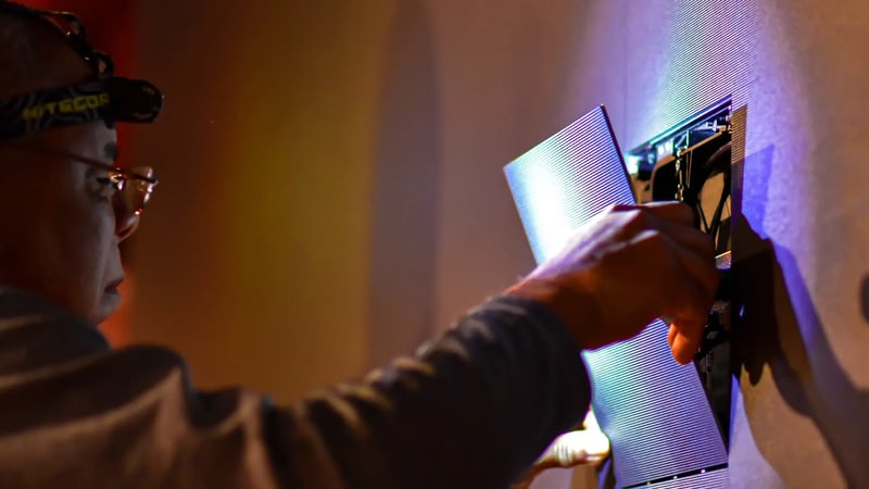 A skilled Electrosonic technician installing LED tiles into a large video wall at a customer site.