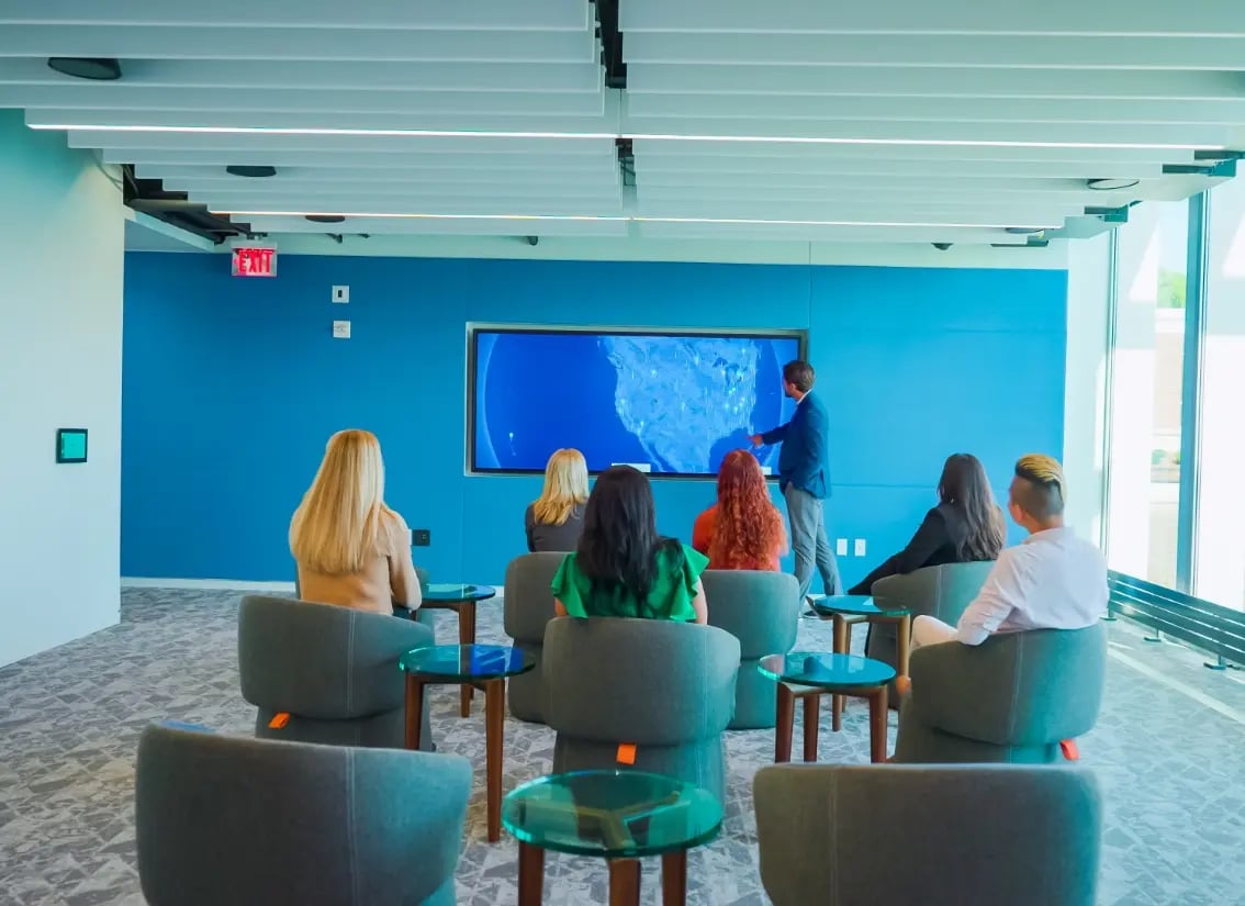 A speaker presenting a sales message to a group of visitors within an experience sales center.
