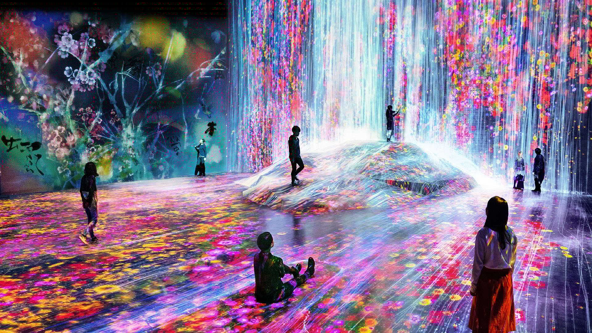 A vibrant immersive art installation features cascading digital waterfalls and colorful floral projections, creating an interactive and dreamlike environment for visitors.