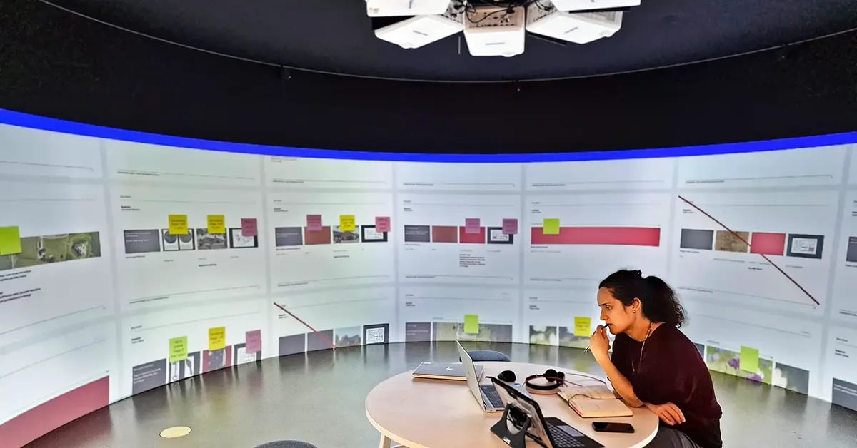 A woman sitting in an immersive meeting room completing her work.