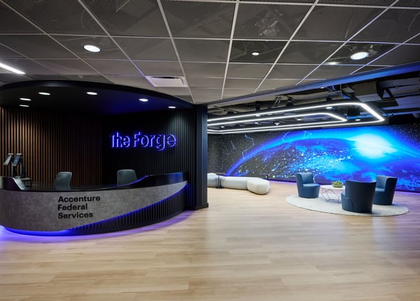 The entrance of the Accenture building with desks on the left with chairs and LED wall on the right.