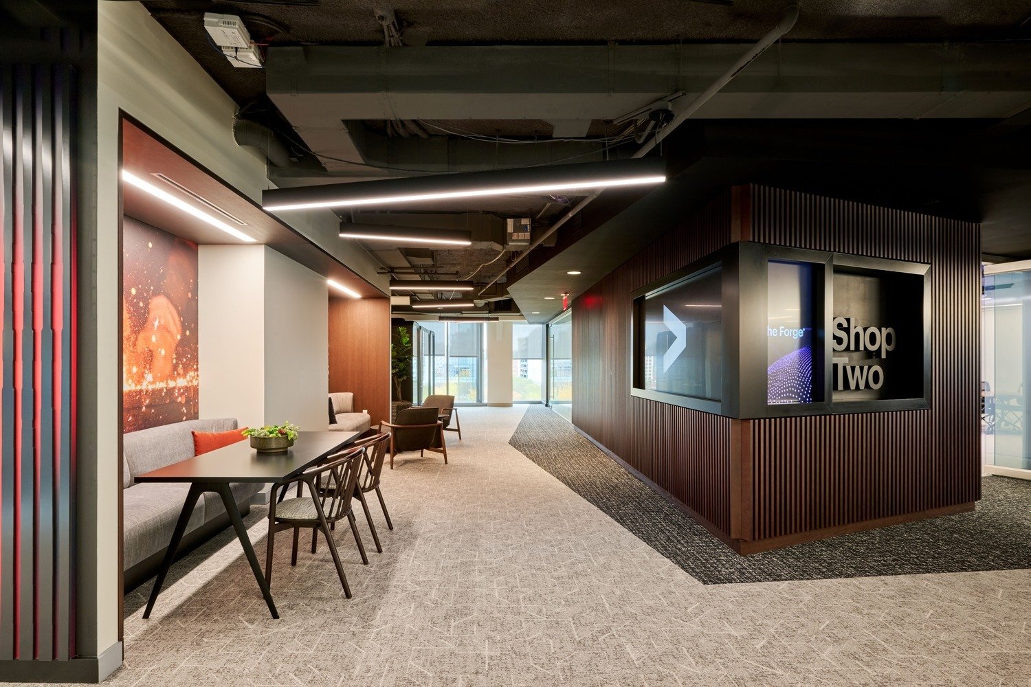 A hallway with chairs and tables on one side and a wall on the other.