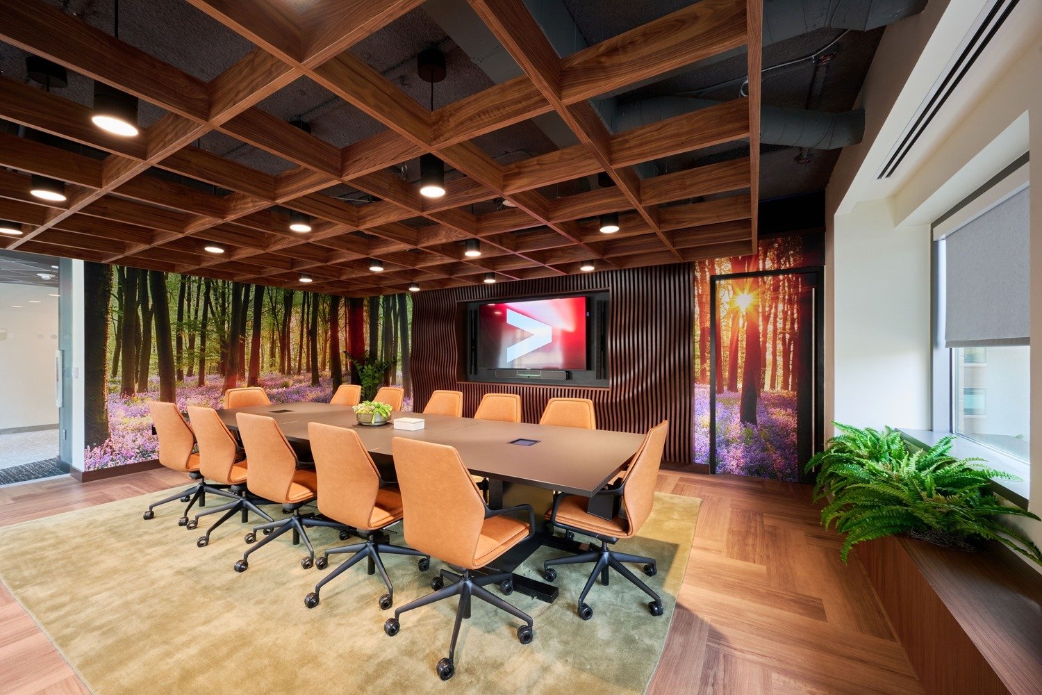A meeting room with a LED screen on the wall.