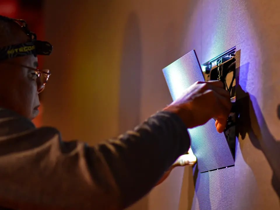 An Electrosonic technician installing LED tiles into a large video wall at a customer site.