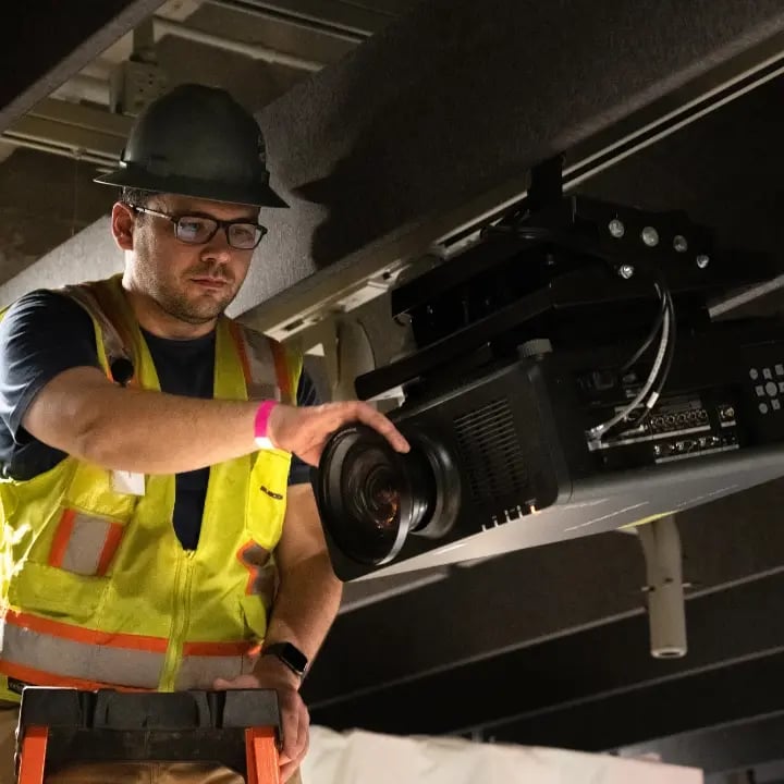 An Electrosonic technician calibrating an installed projector.