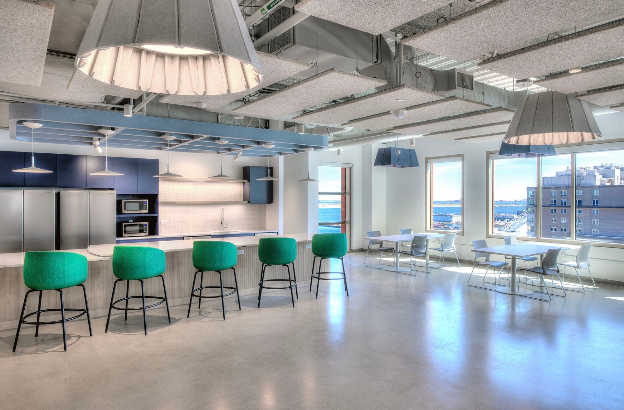 Kitchen with 5 green chairs, 2 refrigerators, and a city view out the windows.