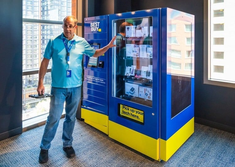 Man pointing at a best buy vending machine with health related items inside