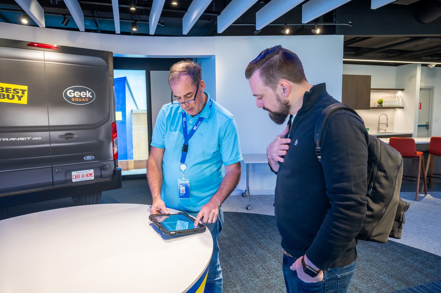 Two men looking at a tablet on the table.