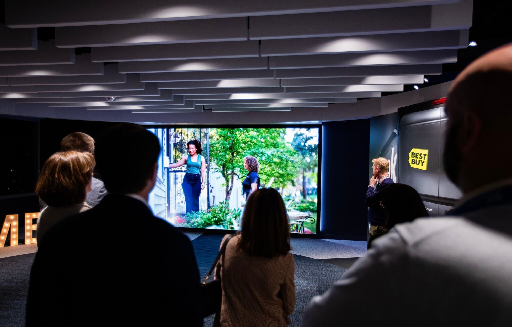 Group of people looking at a large display screen.