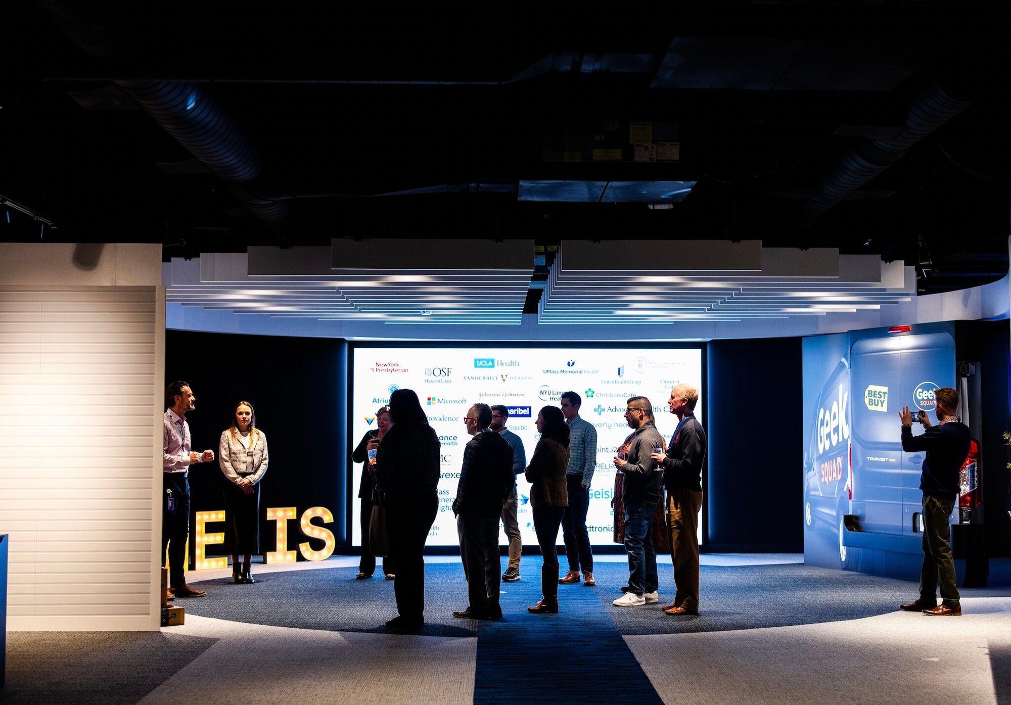 Gorup of people talking in front of display screen.