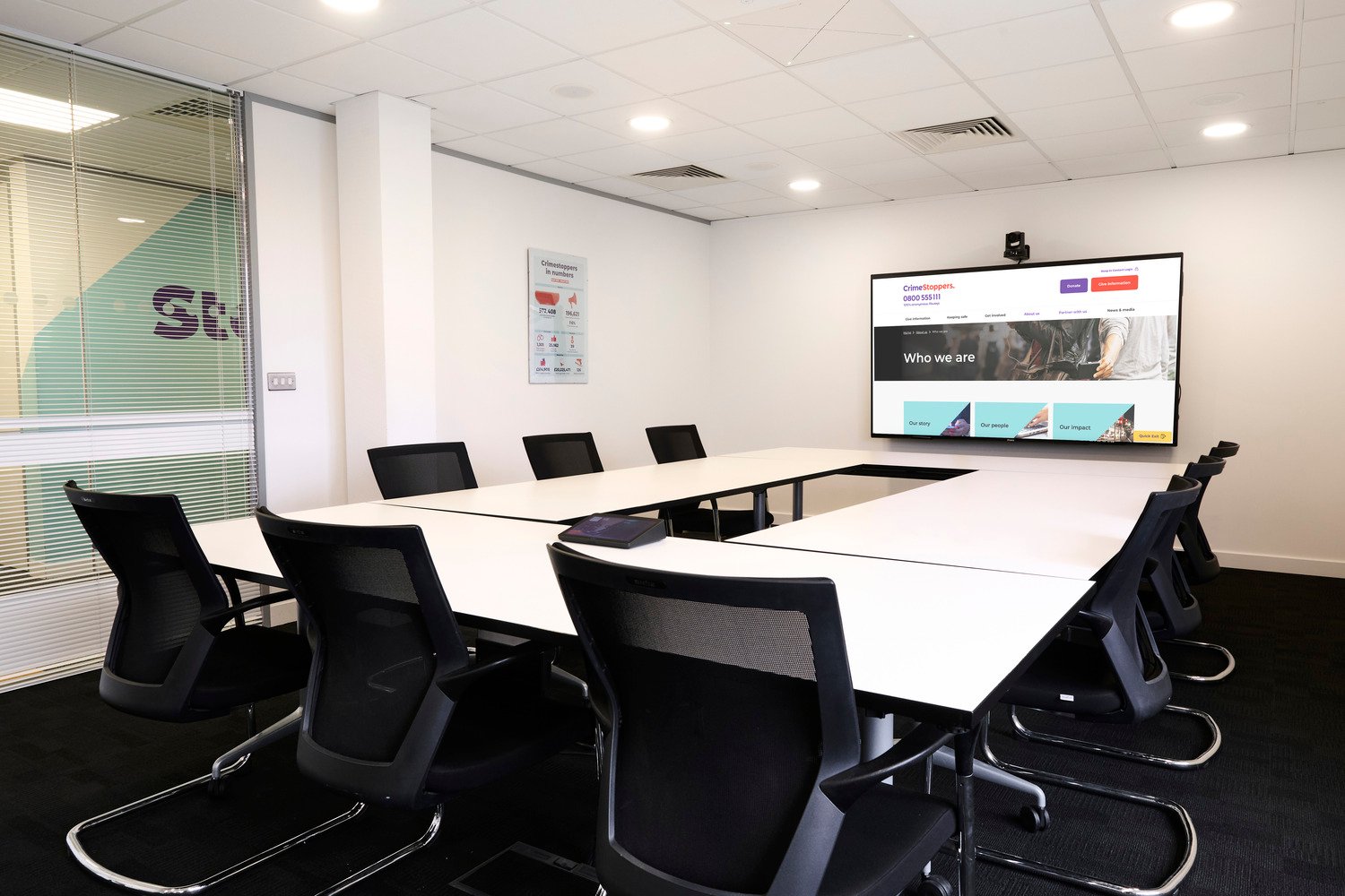 A screen at the end of the room with a square of table and chairs.