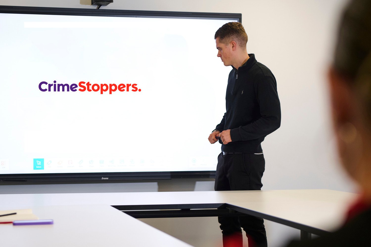 A guy looking at the interactive display with Crimestoppers logo on it