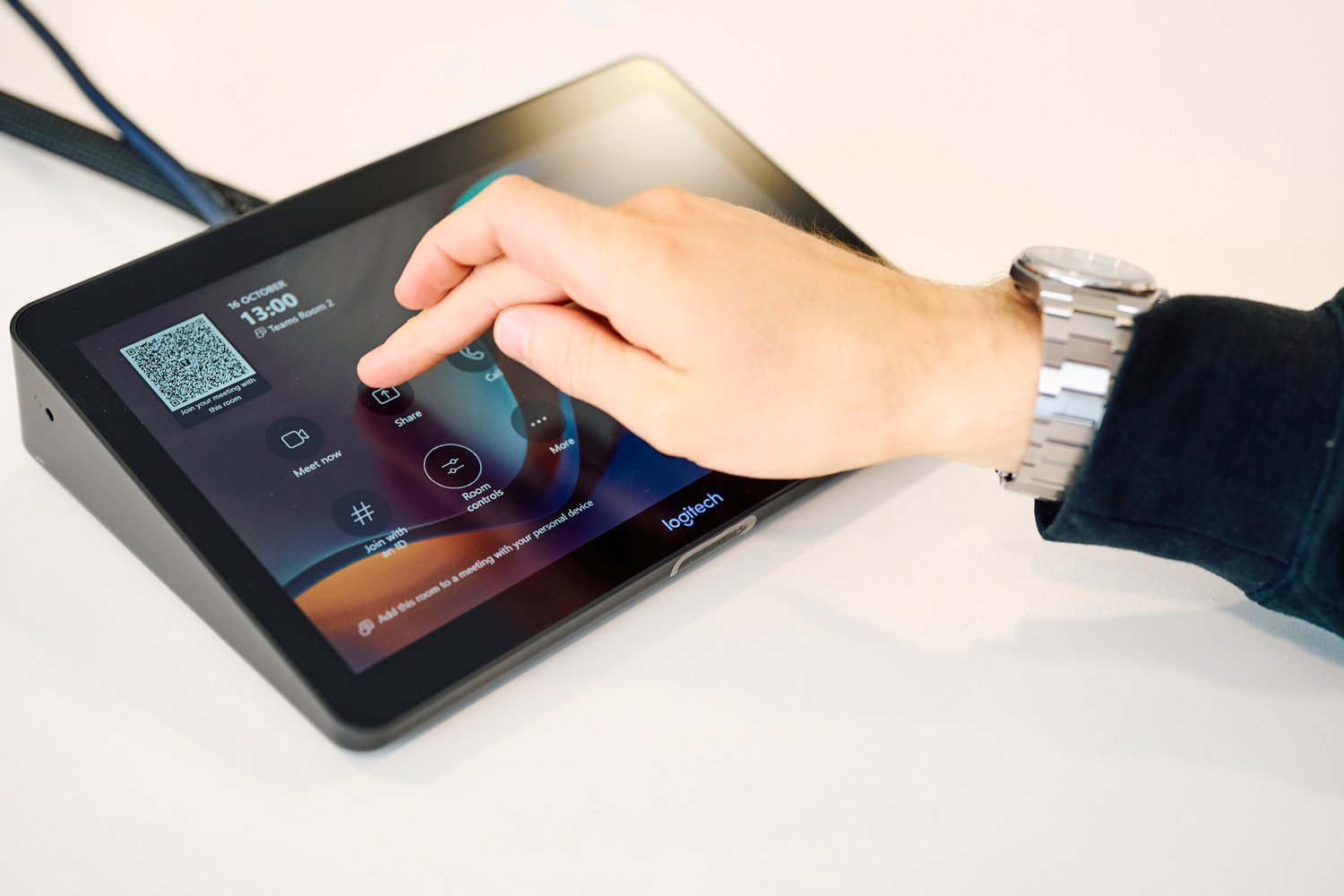 A hand touching an interactive screen that controls the main display.