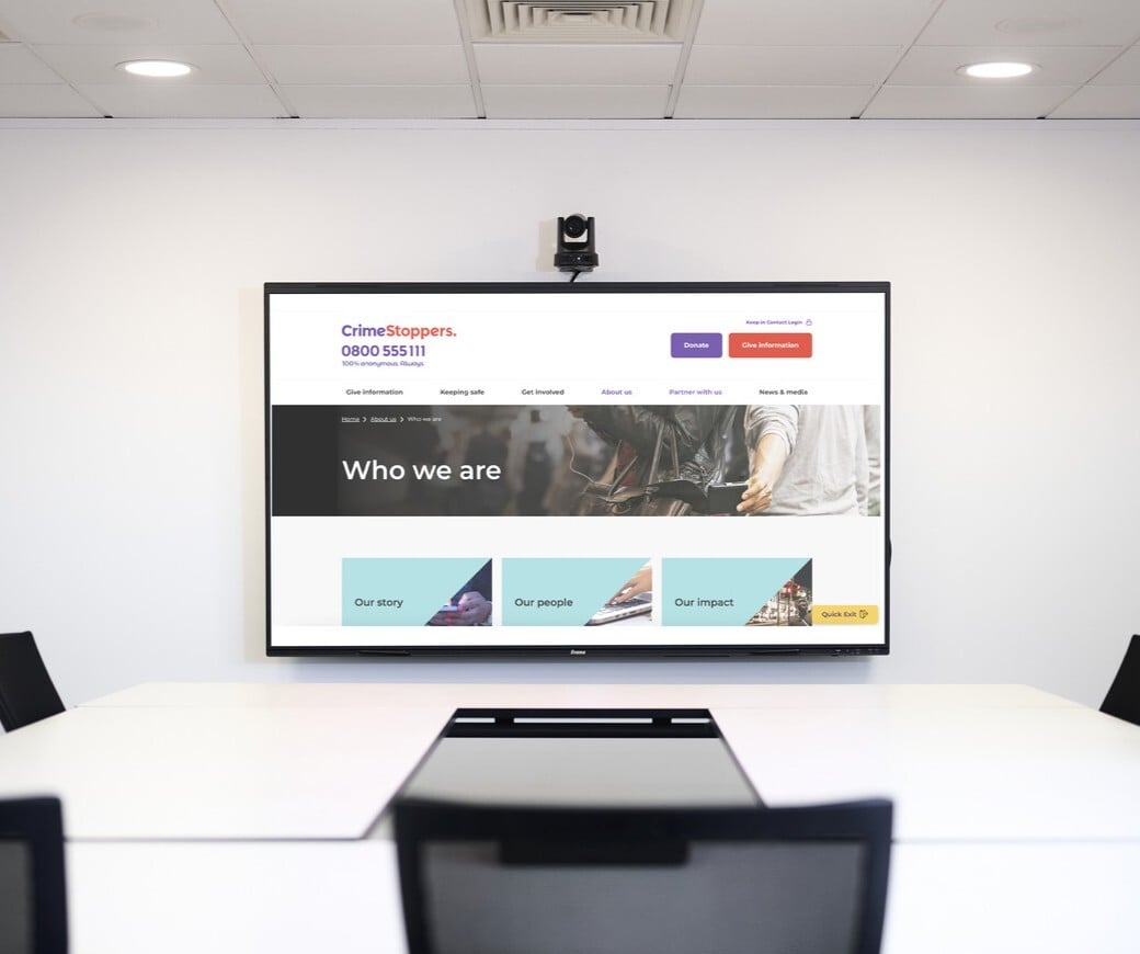 A screen display that is in front of the wall with chairs and tables