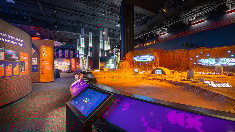 Exhibit photo of Mars: The Next Giant Leap at the Carnegie Science Center, featuring a detailed miniature Mars colony surrounded by interactive touchscreens and futuristic educational displays.
