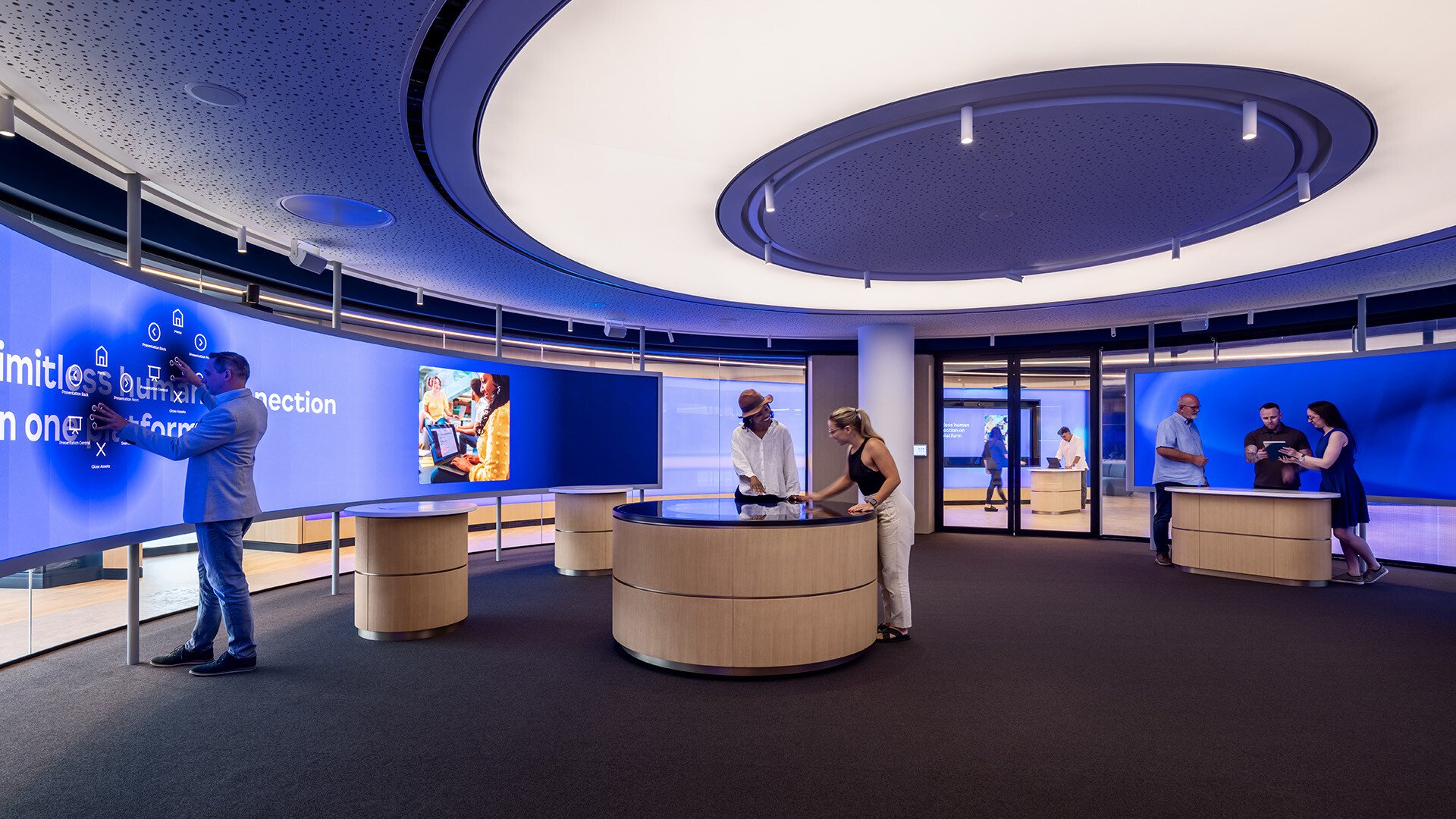 Customers interacting with touch tables and a curved LED wall at Zooms London Experience Center.