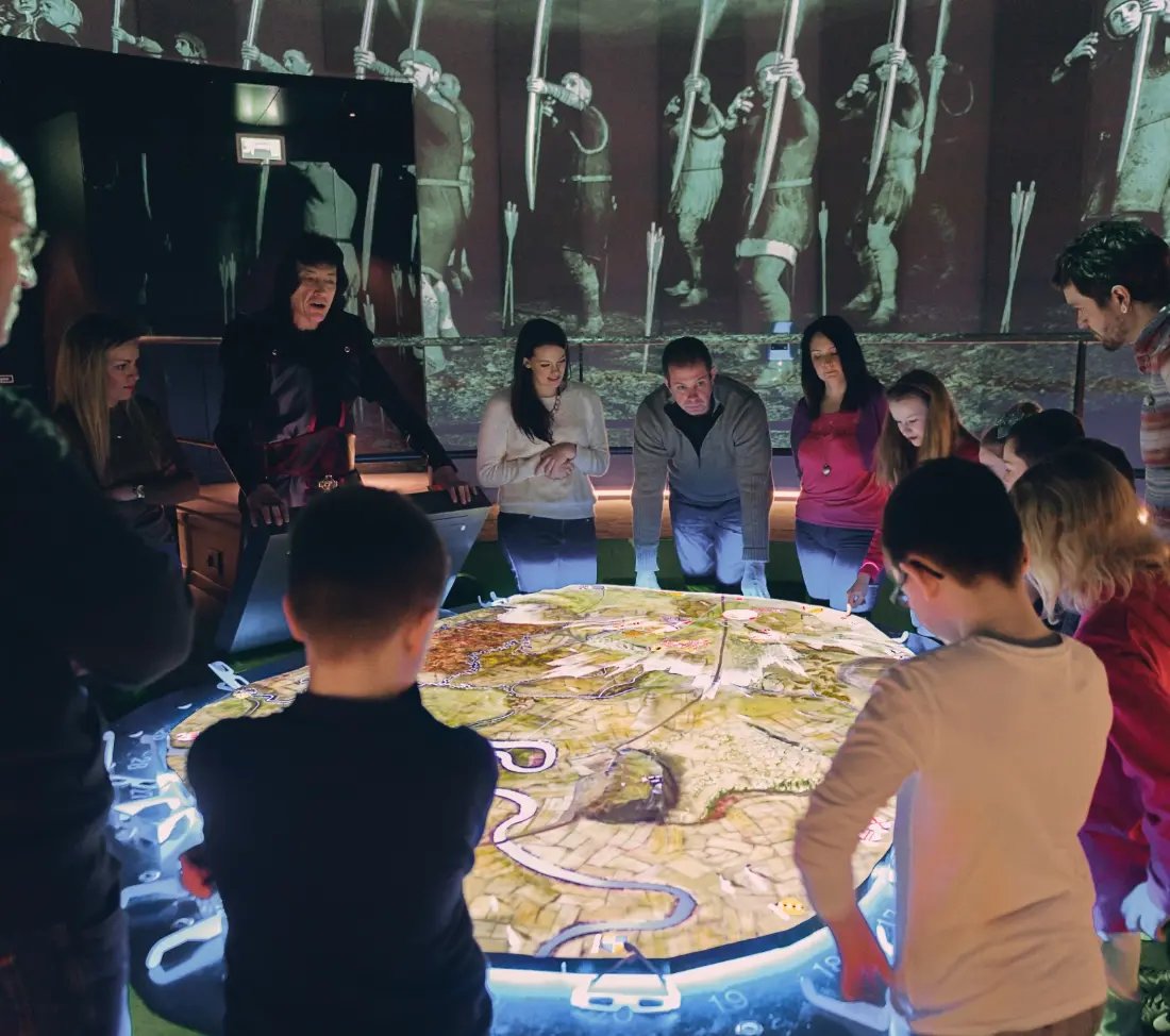 Guests to the Battle of Bannockburn Visitor Centre interacting with the projection based battle map exhibit.
