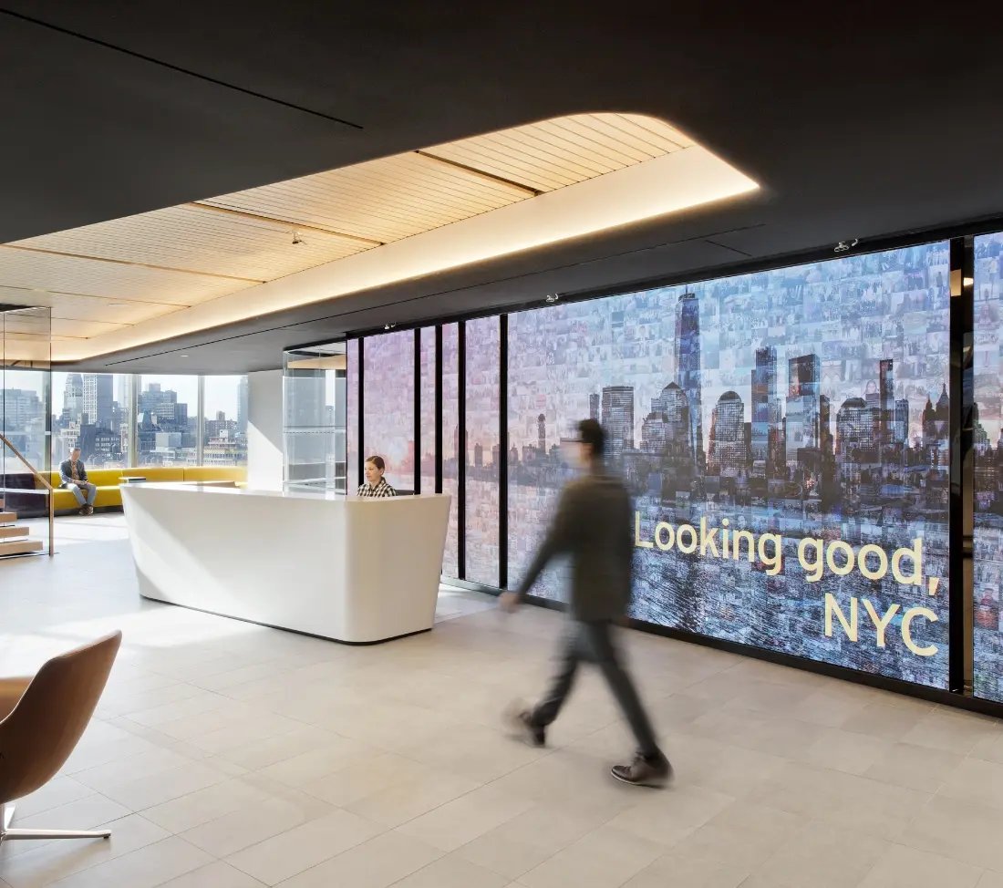 Employees walk past LED wall at large NYC HQ offices.