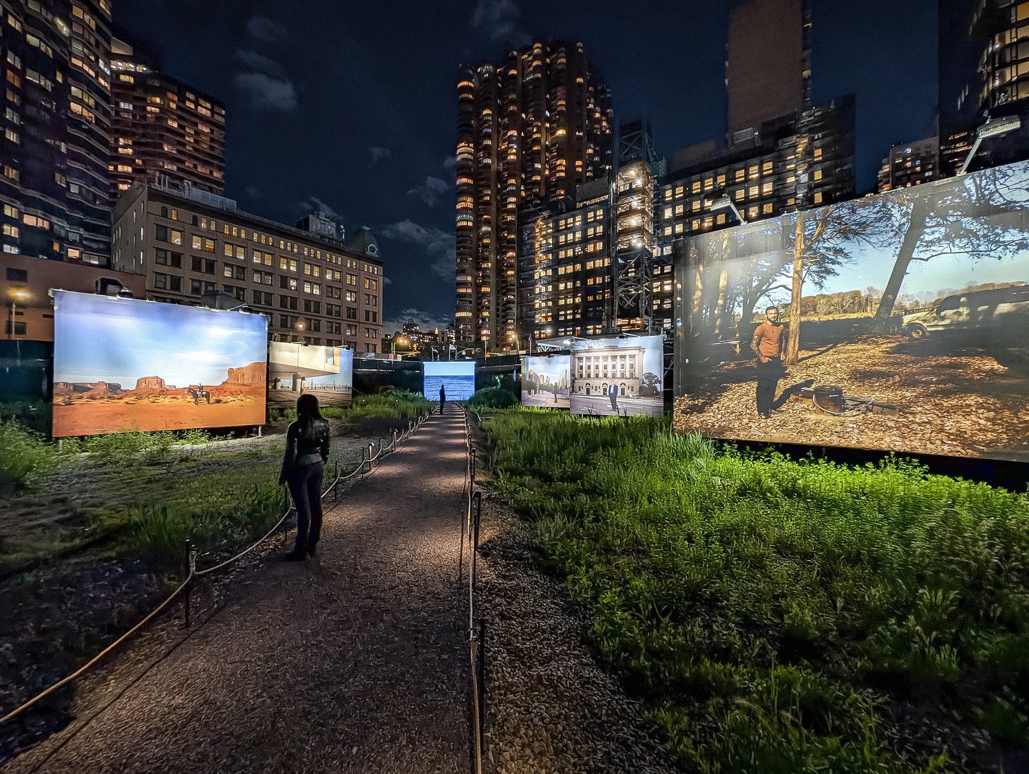 Screen displays of American Landscapes lining the sides with people walking in the middle.