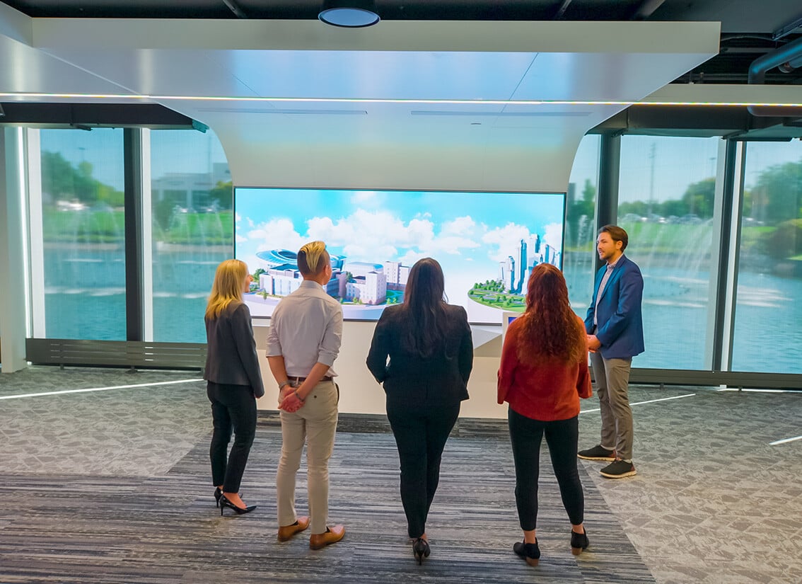 Four customers standing infront of a high definition video wall during a tour of the Johnson Controls innovation center.