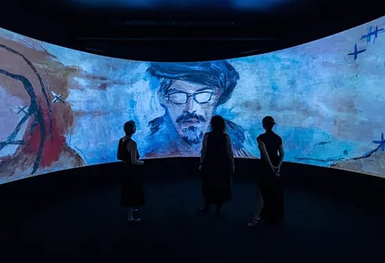 Guests standing infront of a large curved projection experience, the content is showing Johnny Depps artwork.