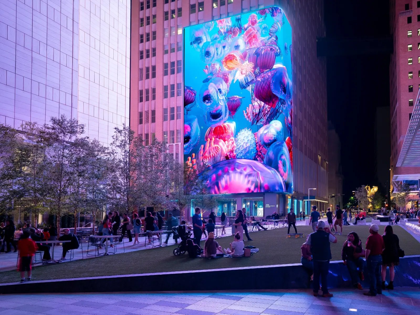 Guests to the AT&T Discovery District walking through the courtyard while a massive LED Video Wall illuminates above them.