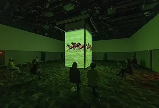 Guests to the National Racing Museum and Hall of Fame watching the show on a four-sided projection mapped box.