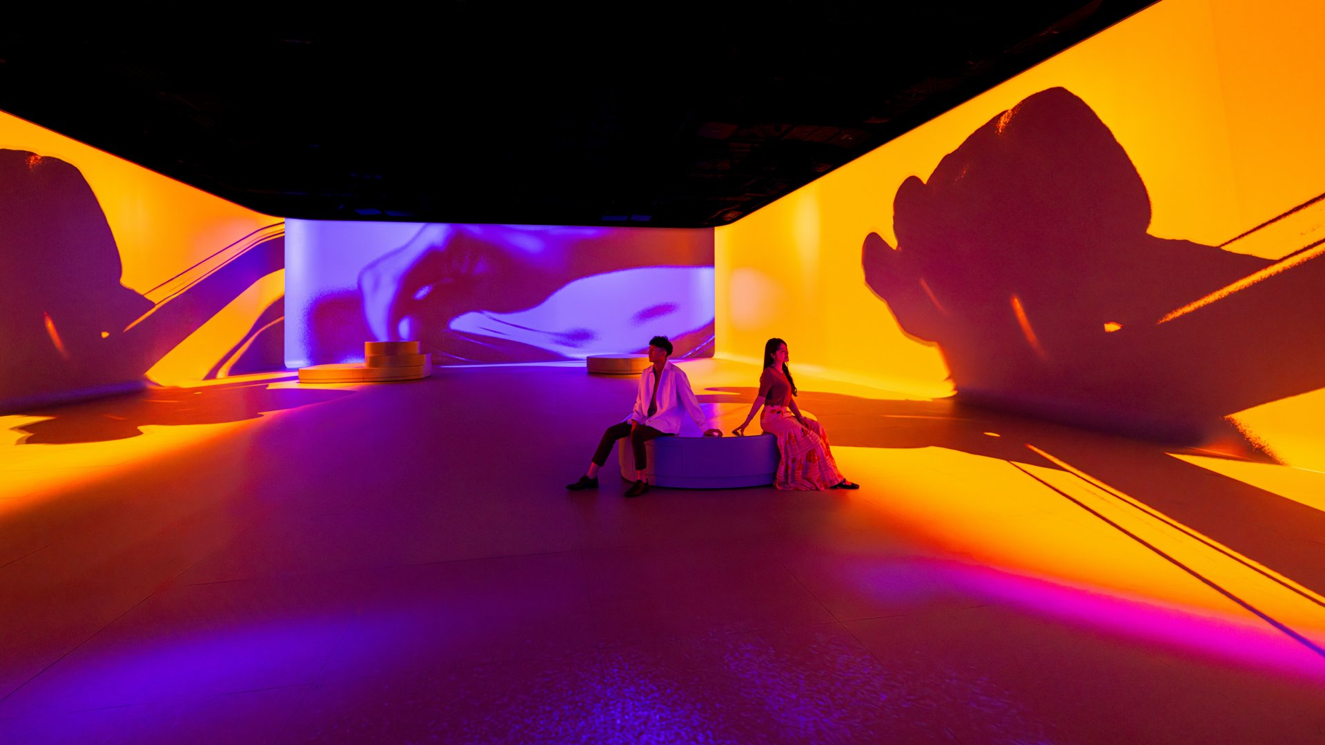 A futuristic immersive experience showcases a massive projection solution where two visitors are centered in the middle of the experience.