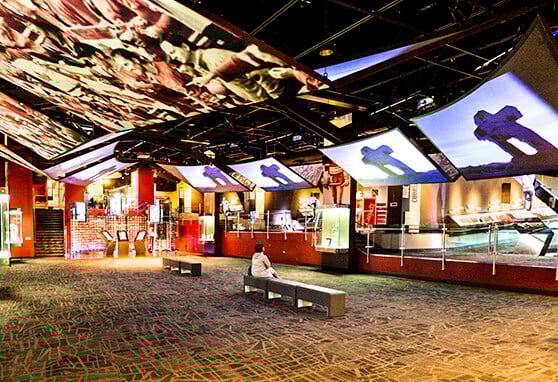 Immersive sports museum exhibit featuring dynamic ceiling projections, interactive displays and curated memorabilia powered by Electrosonic AV solutions.