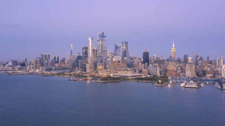 Skyline view of Hudson Yards in New York City featuring modern skyscrapers, the Vessel structure and the surrounding urban landscape at sunset.