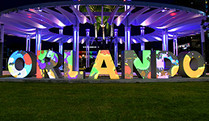 Luminary Nights on the Green in Orlando features a beautifully lit outdoor space adorned with glowing lanterns and twinkling string lights. Families and visitors stroll through the festive scene, enjoying the warm, inviting atmosphere of this community celebration.