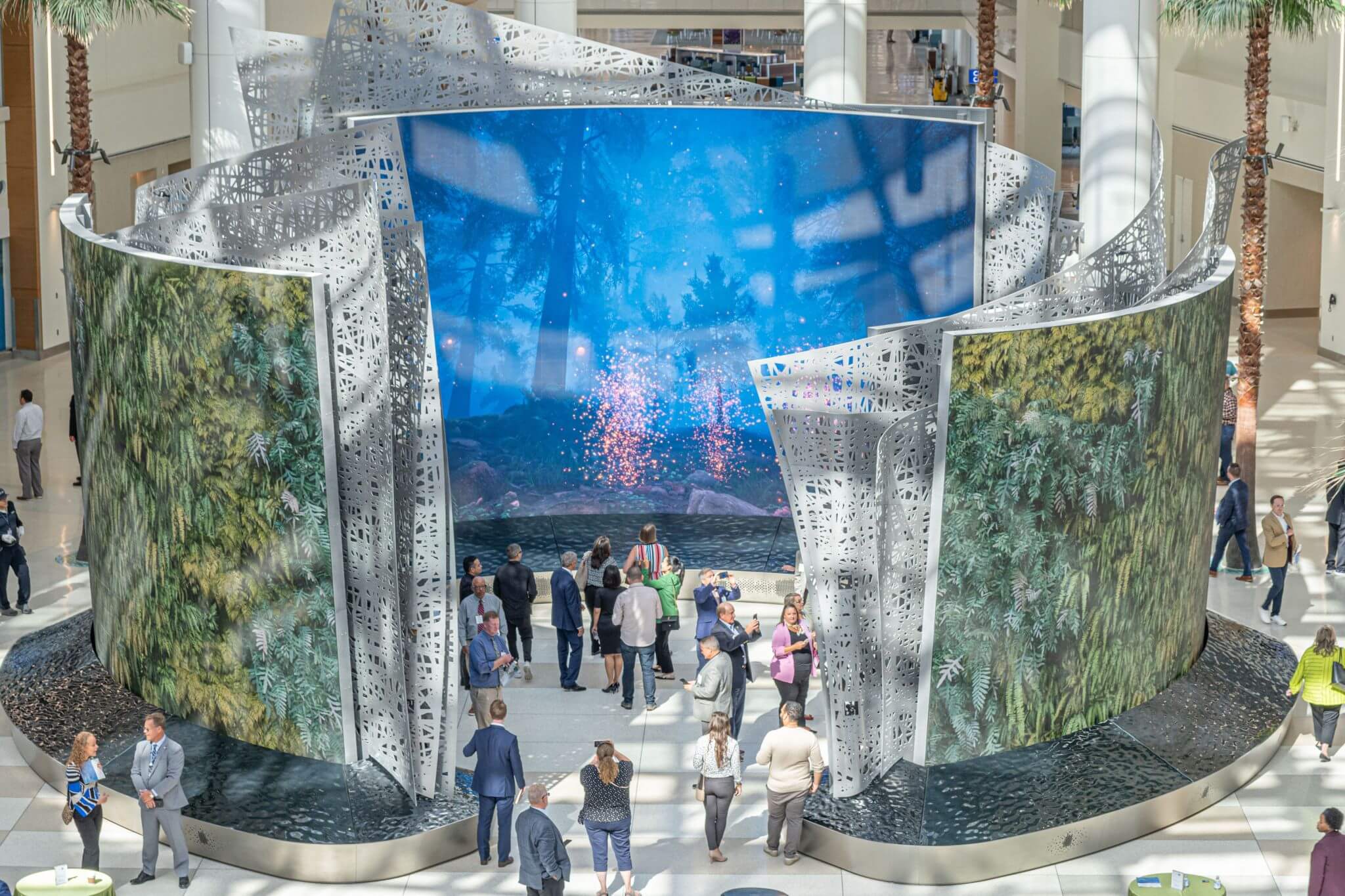 Large dual-sided LED walls within Orlando International Airport. Travelers are walking through the installation interacting with it. 