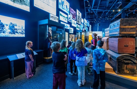Group of children walking through room with LED screens on the wall.
