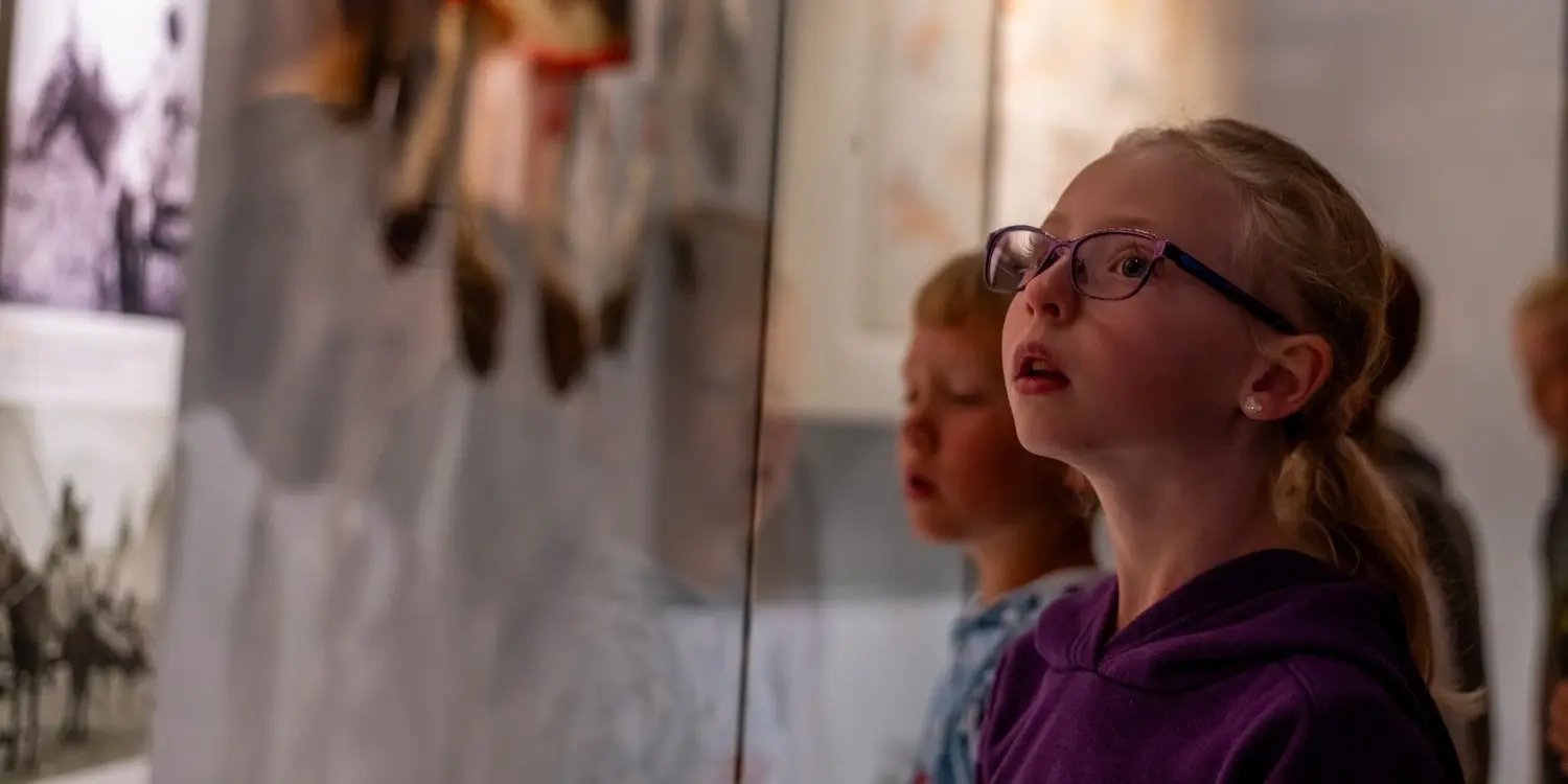 Girl looking up at artifacts in glass.