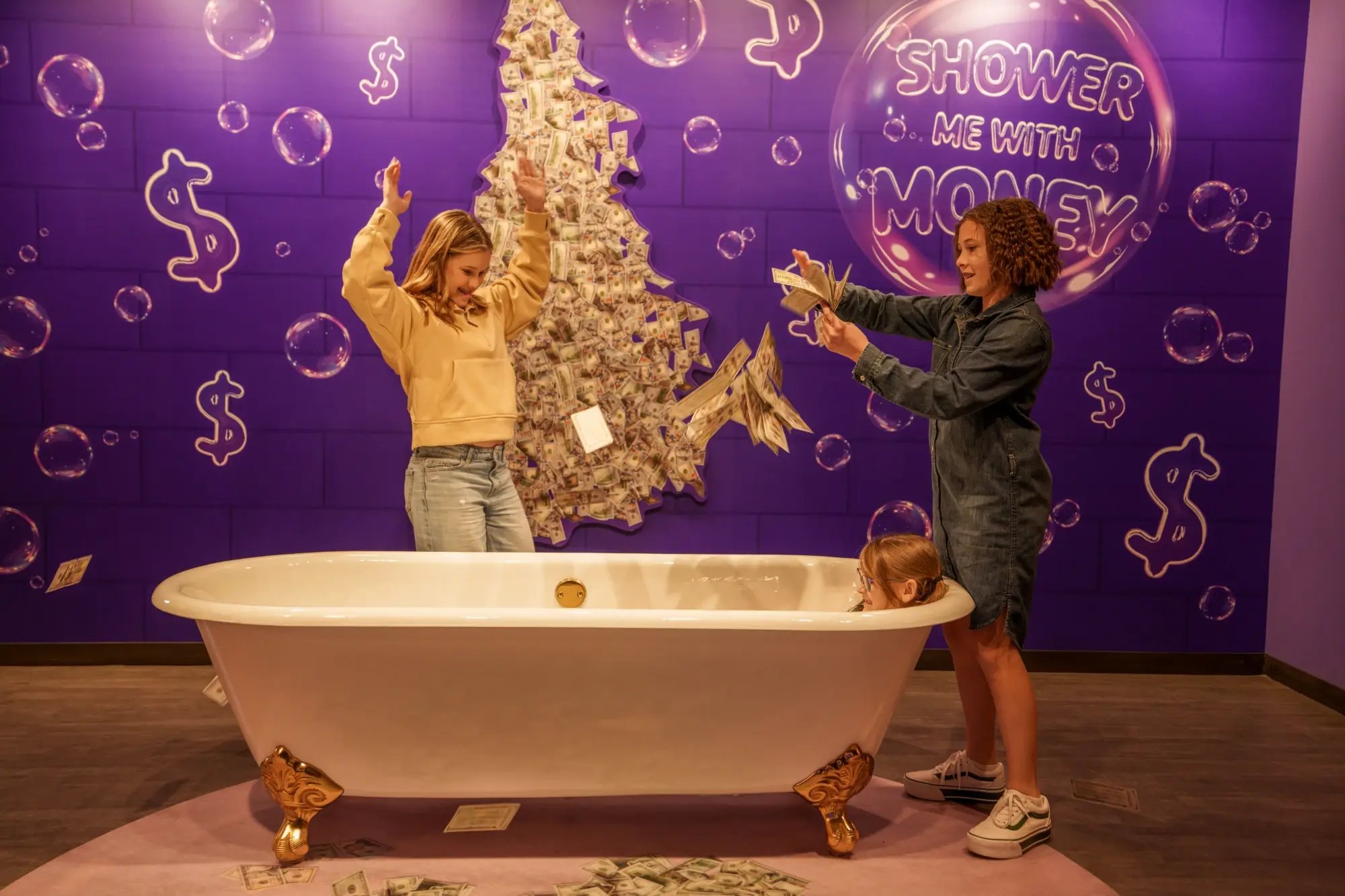 Two girls playing with money in a bathtub