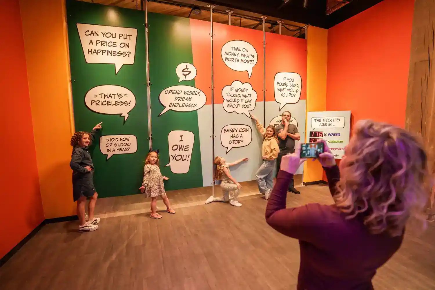 Women taking picture of people in front of photo op wall.