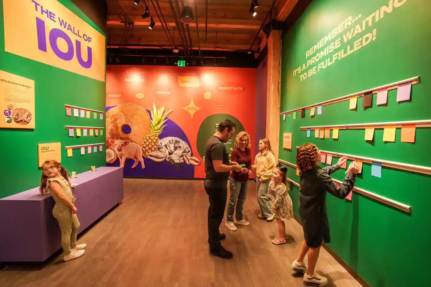 People in a hallway interacting with 'The wall of IOU"