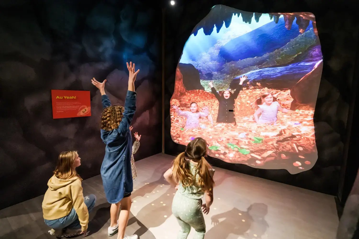 Four kids playing with the goldmine projection.