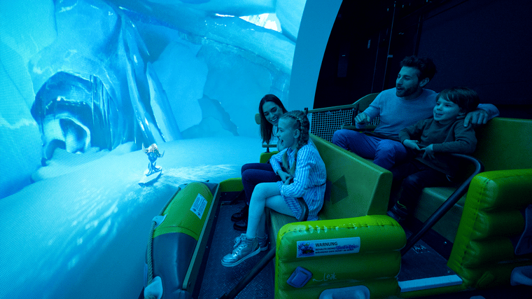 Colorful interior scene from Snorri Touren, featuring guests in ride vehicles journeying through whimsical underwater-themed environments with animated characters, lighting effects and detailed set design.