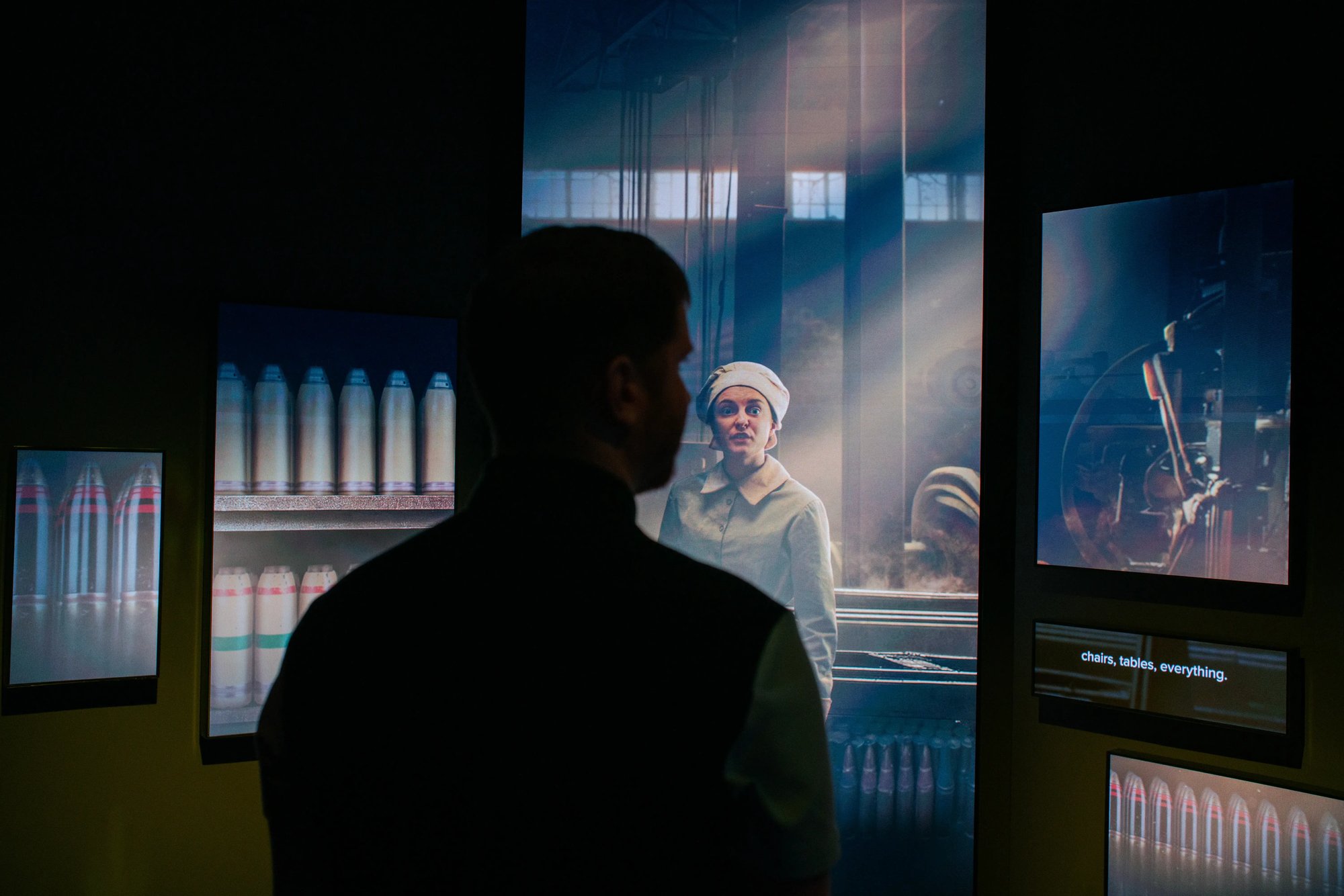 A man looking at a woman character on a LED screen.