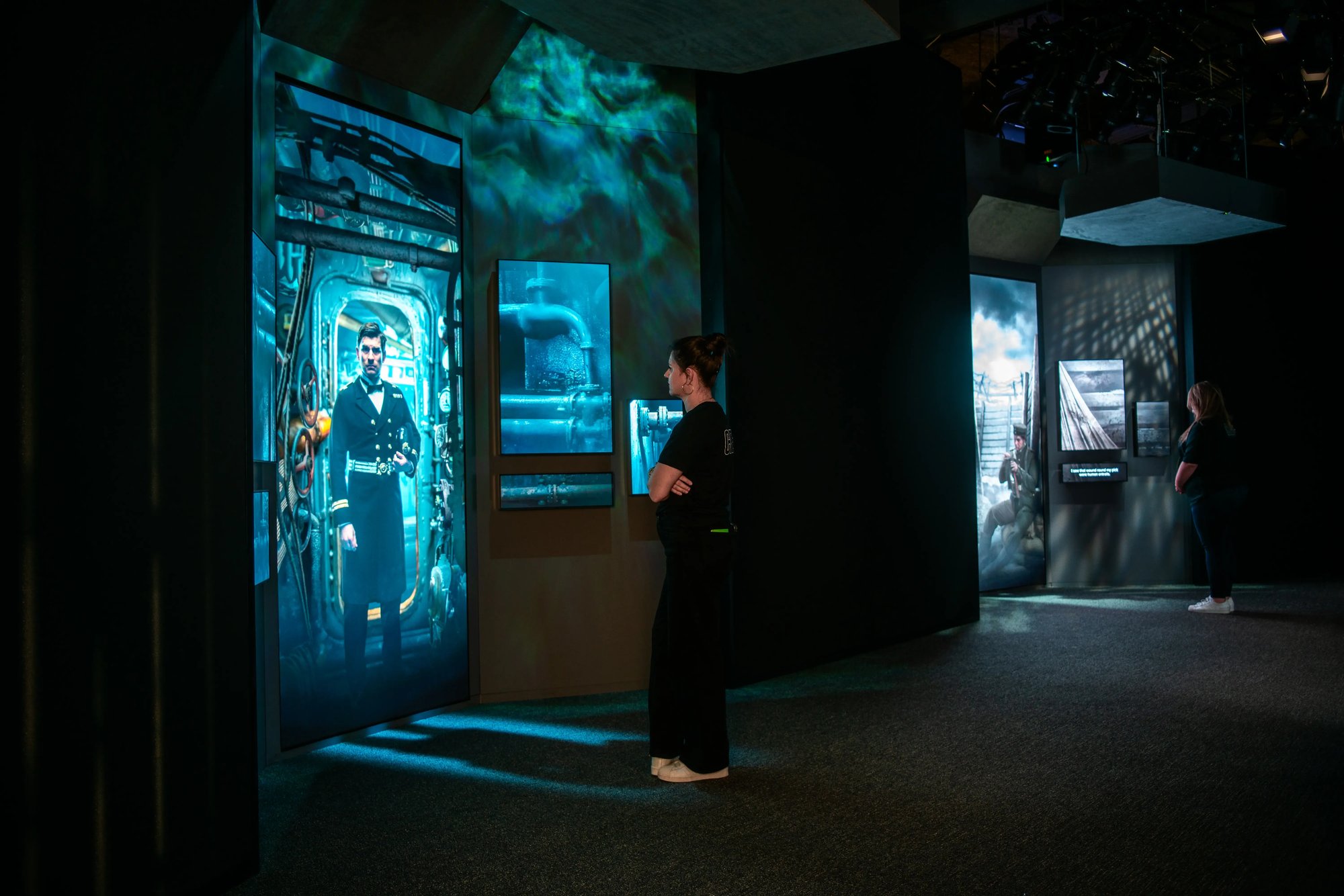 People interacting with characters on a screen in two alcoves.