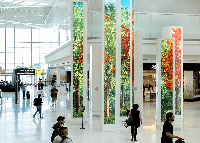 Travelers walking past digital LED totems at the Newark Liberty International Airport Terminal A. 